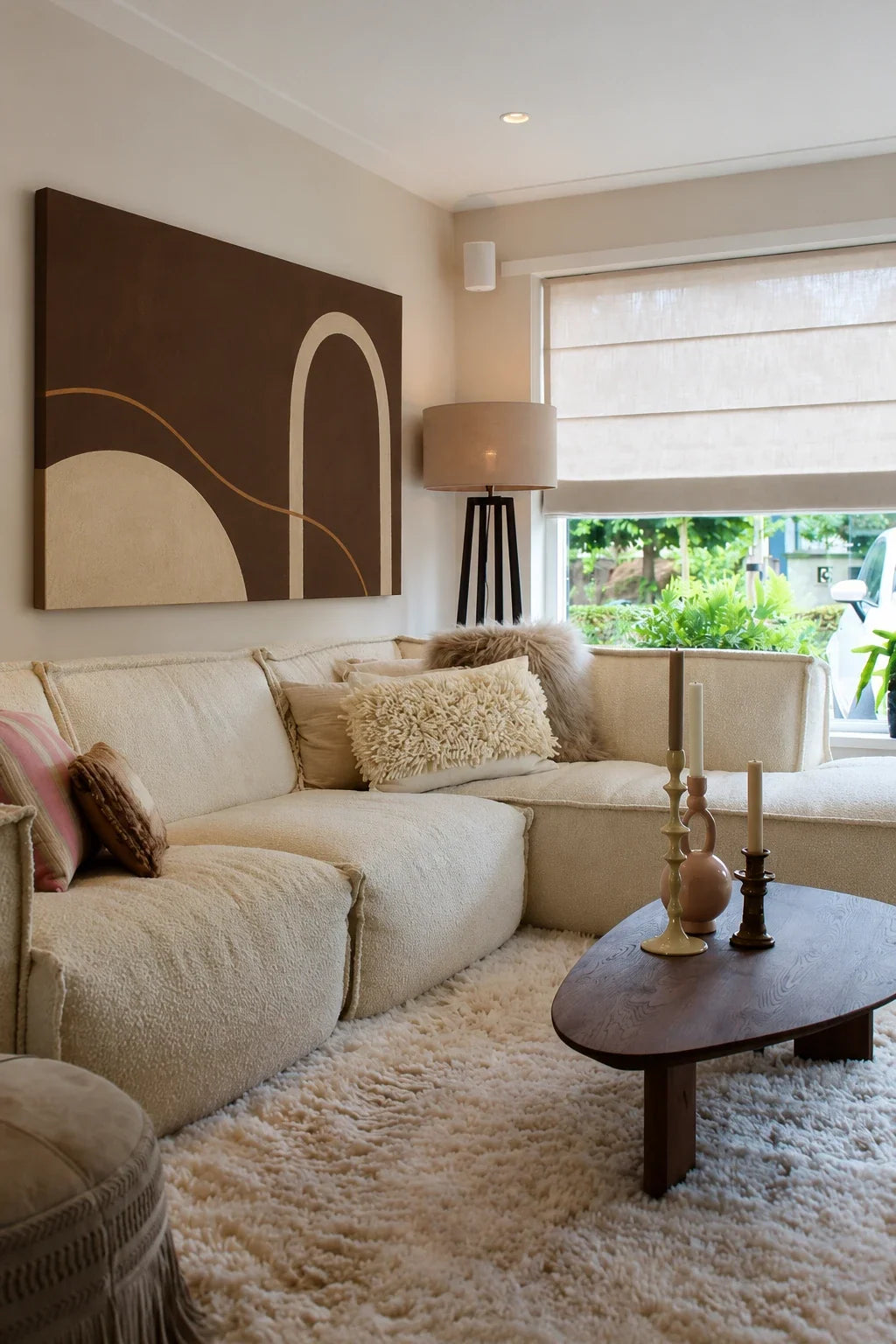 Lichte woonkamer met crème hoekbank en een groot donkerbruin abstract canvas
